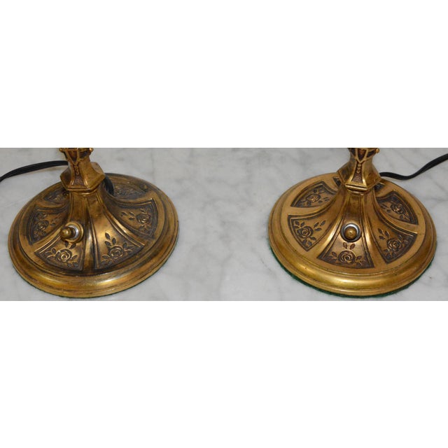 A pair of Art Deco style cast bronze metal table lamps with hand blown Tiffany style iridescent shades. This pair of lamps...