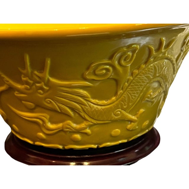 A pair of early 20th century Chinese imperial yellow Peking glass bowls with dragon design. On ornate wooden stands. Bowls...