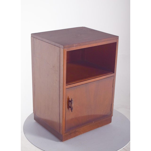 Bedside table with one door. Its cubic and compact structure emphasises simple and practical geometry, evoking a modernist...