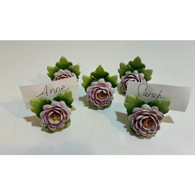 A beautiful set of nine vintage German porcelain place card holders featuring hand-sculpted pink roses purple flowers with...