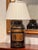 Tea tin lamp in black paint with gilt bands and a gilt panel of characters, numbered 32, fitted with a pleated shade.