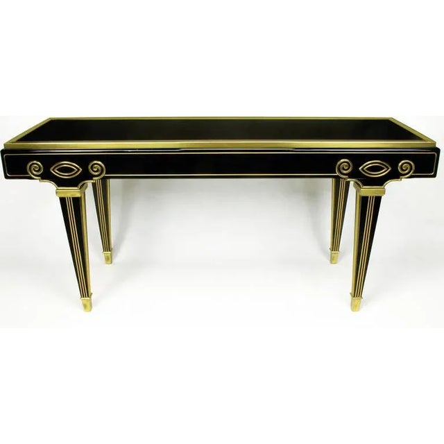 Elegant black lacquer and brushed brass Empire style console table by Mastercraft. Finished on all four sides with brass...