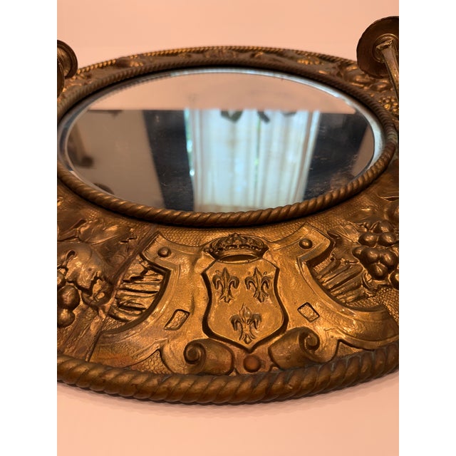 This exceptional antique wall mirror features a heavy brass frame beautifully decorated in relief with classic...