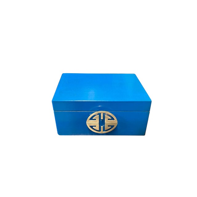 This is a decorative box in a rectangular shape and matte light golden color round hardware accent. The surface is a layer...