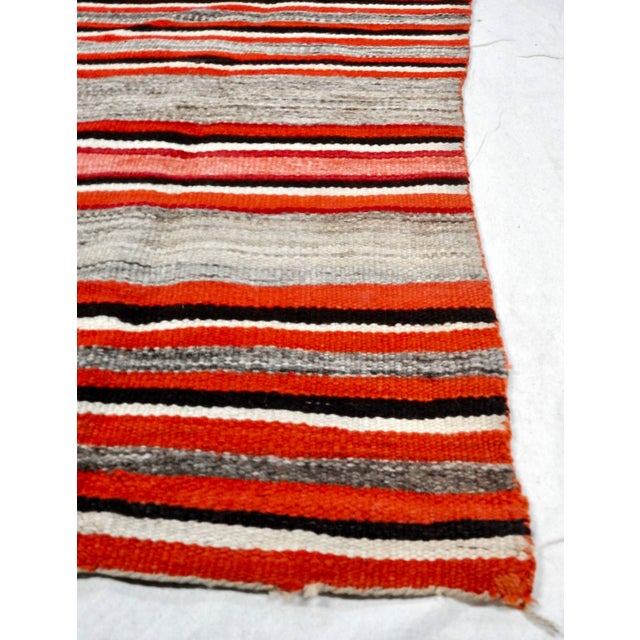 Featured is an antique, circa 1890s handwoven Navajo transitional wool rug. The rug features bold stripes of various...