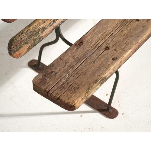 This antique bench in iron and pine wood is a Central European station bench with a cold-bent flat-bar frame and solid...
