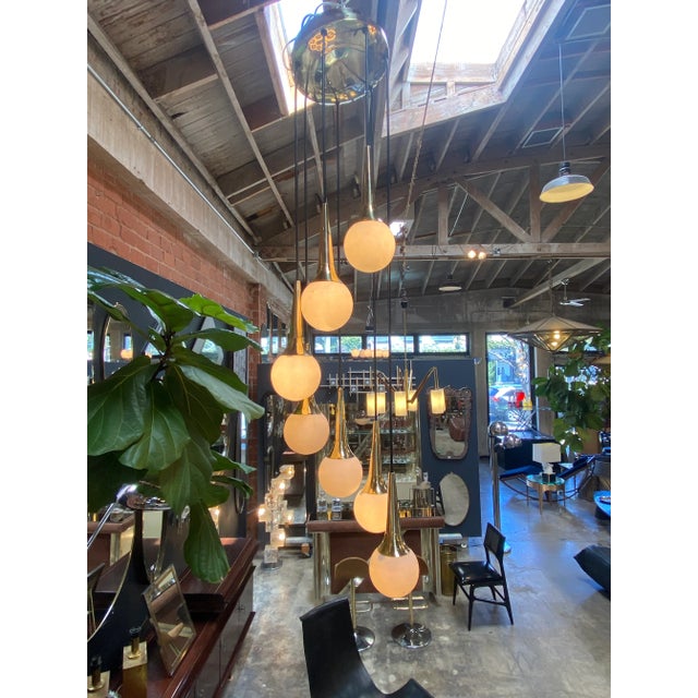 Mid Century modern cascading chandelier Attributed to Stilnovo with seven opaline glass ball lights supported by brass...