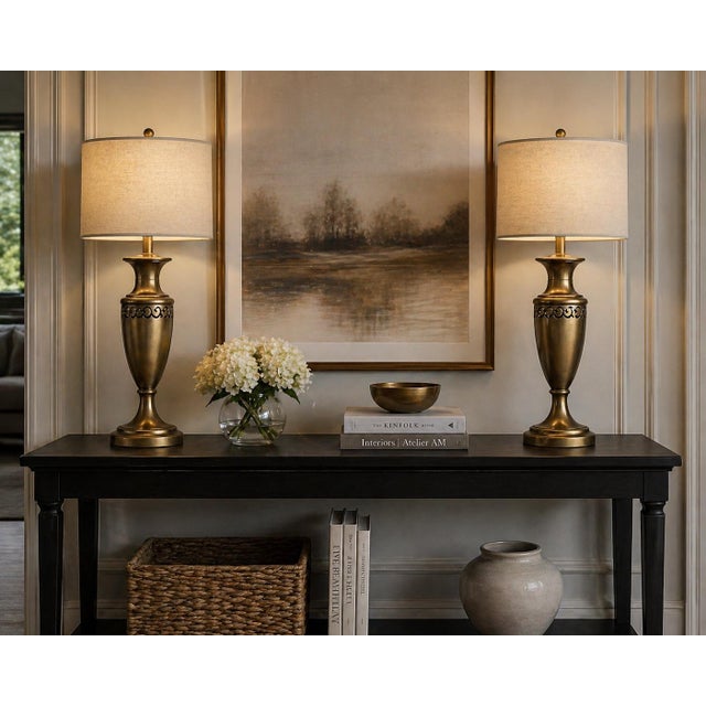 A refined pair of vintage urn-form table lamps finished in warm antique brass, distinguished by a pierced metal frieze...