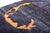 A single bold orange crescent curls across a deep, moody evening-blue field — dramatic, sculptural, and unmistakably...