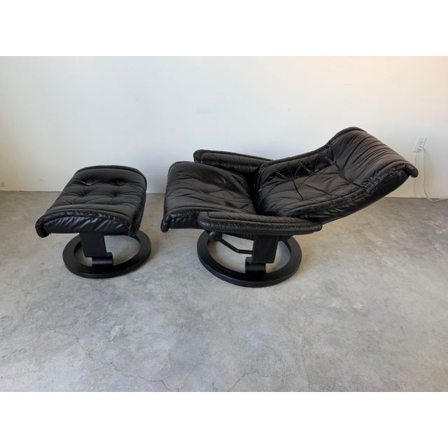 Classic vintage Ekornes Stressless recliner and matching ottoman crafted in Norway, featuring supple black leather...