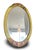 Oval wall mirror with a carved and polychrome painted wooden frame in shades of yellow and pink. The frame is decorated,...