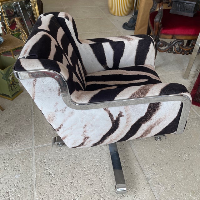 AI Overview This swivel armchair features a modern design upholstered in a zebra-printed pattern on a metallic base,...