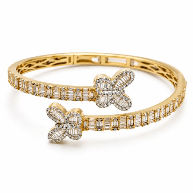 Structured and richly detailed, this 10K Yellow Gold designer bangle is set with round and baguette-cut natural diamonds...