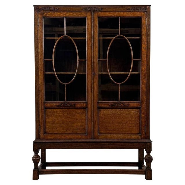 A handsome early 20th-century English display cabinet, finely crafted from oak and distinguished by its elegant glazed...