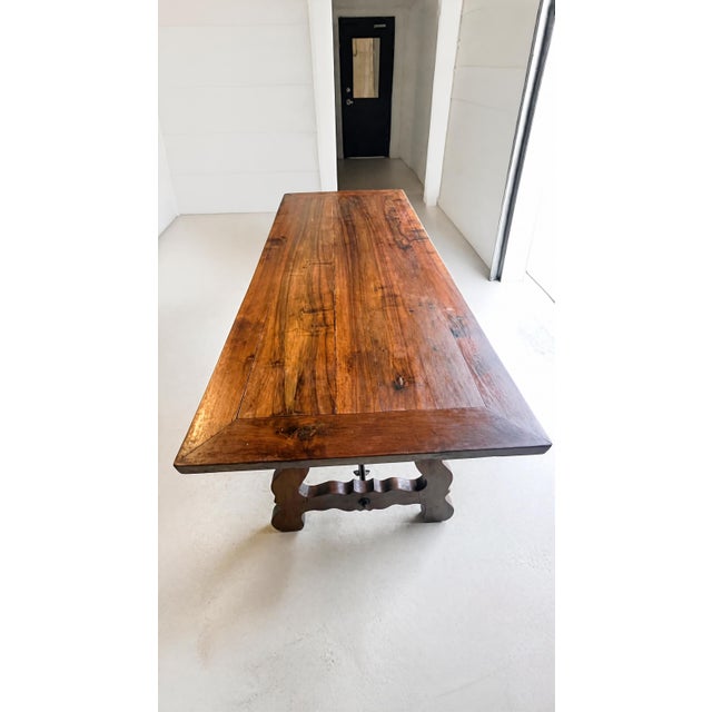 Late 19th-century Spanish trestle table with a richly grained wood top and distinctive wrought-iron base. Its hand-...