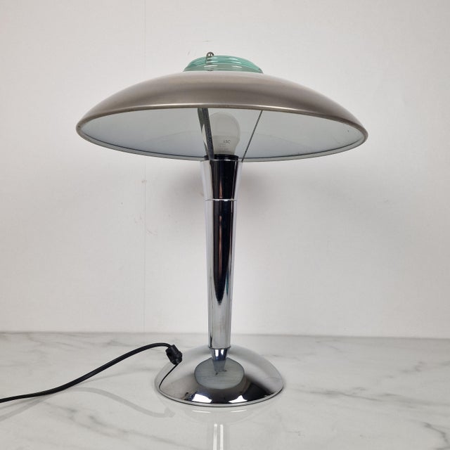 Elegant vintage table lamp featuring a sleek chrome base and a distinctive dome-shaped shade. The design is beautifully...