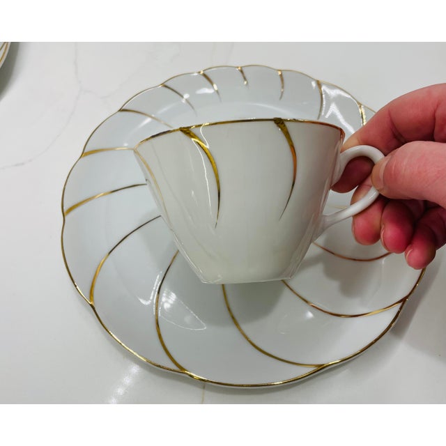Elegant set of four white porcelain teacups with matching tea plates featuring a distinctive gold spiral design. Unlike...