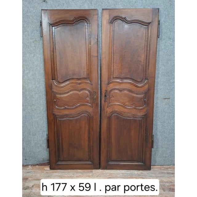 A beautiful pair of Louis XV period walnut doors featuring elegant molded decoration with scalloped panels. Each door leaf...