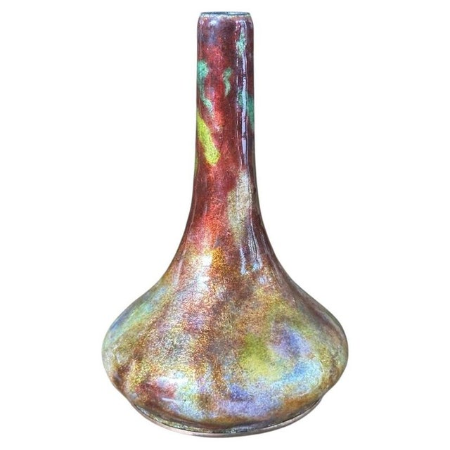 Rich iridescent flambé enamels cover this compact soliflore vase, graduating from mottled ruby red at the slender neck...