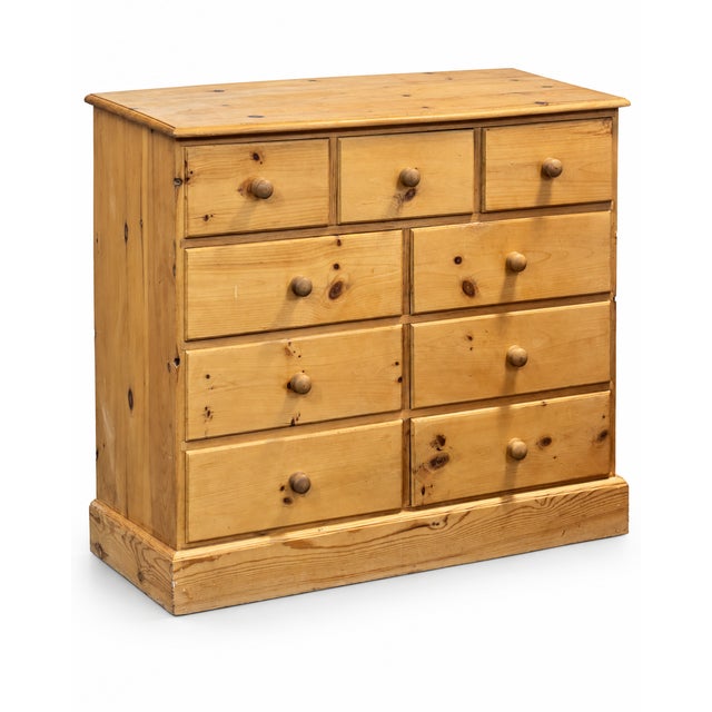 A substantial vintage pine chest of drawers dating from around the mid-20th century, with a particularly practical nine-...