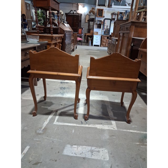 A beautifully matched pair of mid-century French Provincial bedside tables in the Louis XV style. Each piece features a...