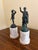 A pair of Grand Tour–style classical figures in brass, mounted on a cylindrical marble bases. The slightly more relaxed...