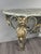 Wrought iron wall console, adorned with gilded scrolls and foliage, topped with a veined marble slab. The wrought iron...