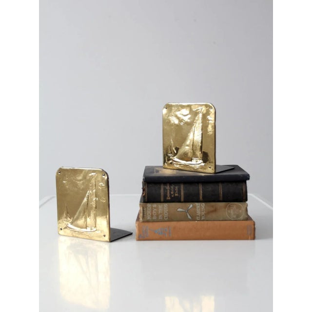 A sophisticated pair of mid-century brass bookends with a refined nautical sensibility. The substantial square forms are...