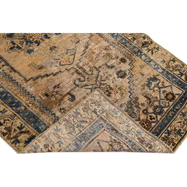 Beautiful vintage Persian distressed hand-knotted wool rug with a tan color field. This piece has navy blue and brown...