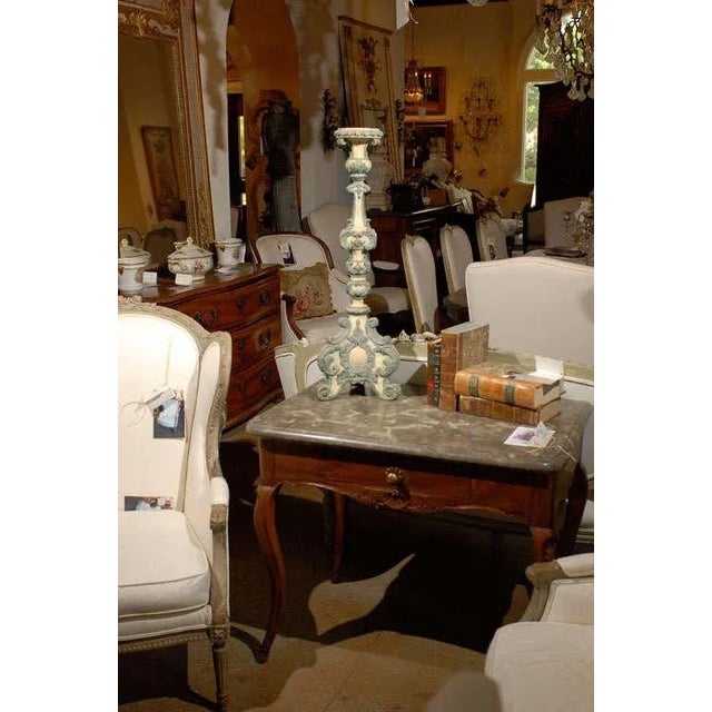 An Italian period Rococo painted and carved wooden candlestick from the 18th century, with blue accents. This exquisite...