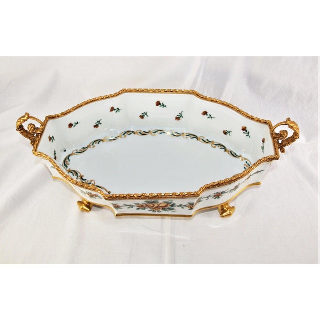 A vintage hand painted French Limoges oval presentation dish. The dish has flowers painted on all sides and inside. Gold...