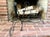 A pair of hand-forged wrought iron Arts & Crafts style andirons with cylindrical scroll-top finials, ring-loop mid-section...