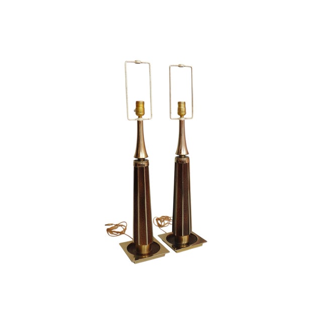 A pair of mid-century modern table lamps circa 1960. Tall columns made of brass are fluted and inlaid with a brown...
