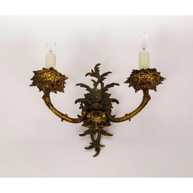 An antique, solid brass organic-shaped sconce with a rich, dark patina. The cast wall mount sprouts acanthus leaves with...