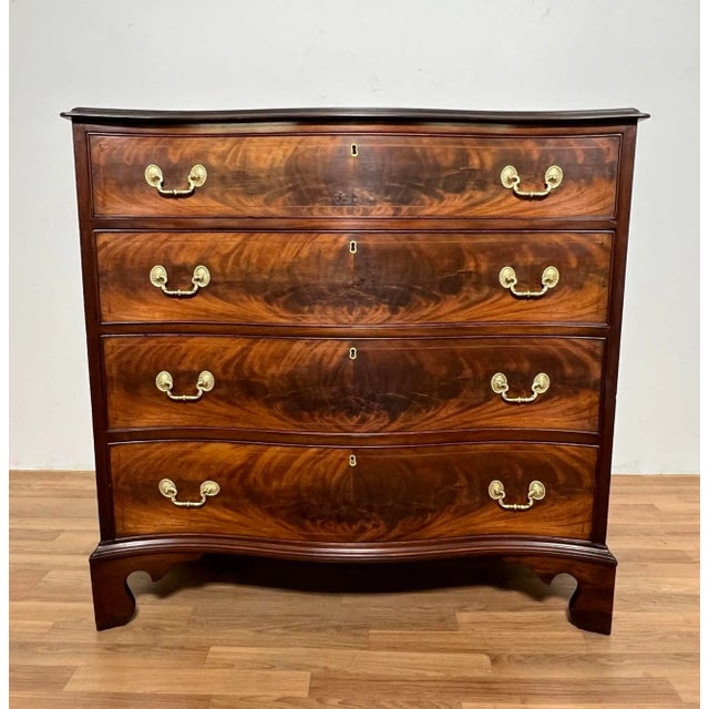A fine antique George III serpentine chest, ca. 1790, with flamed mahogany drawers over bracket feet. Original brasses...