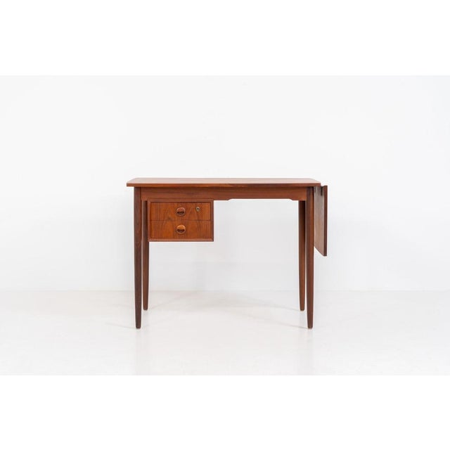 Stunning free standing drop-leaf desk in teak (Denmark, 1960s). It features a cabinet with two drawers and a convenient...