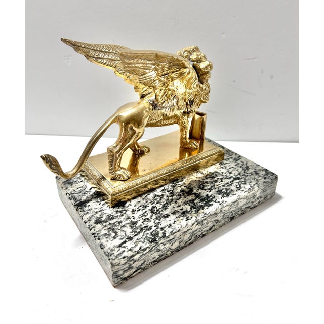 A substantial vintage brass winged lion sculpture mounted on a solid marble base, modeled after the celebrated Lion of...