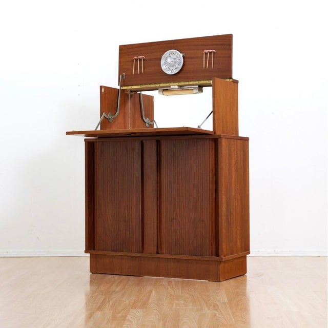 This fantastic mid century bar cabinet was made in England during the 1950s by Sureline. The top cabinet doors open...