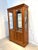 Elegant display cabinet crafted in warm cherry-toned wood with large glass panels, perfect for showcasing decorative...