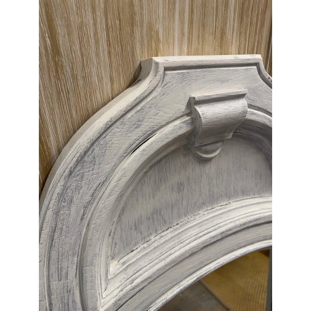 Elegant French Country arched wall mirror featuring top crest detailing and a distressed whitewashed finish over wood....