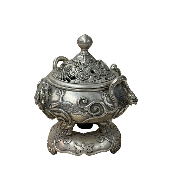 This ornate, heavy-set silver-colored metal censer set comprises three distinct components: a main tripod vessel body, a...