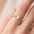 An ethereal, minimalist solitaire featuring a marquise-cut moonstone with a soft blue glow set in an east-west...