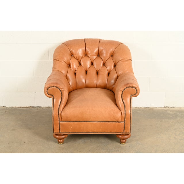 An outstanding late Victorian leather upholstered deep tufted club chair or tub chair with scrolled arms on turned bun...