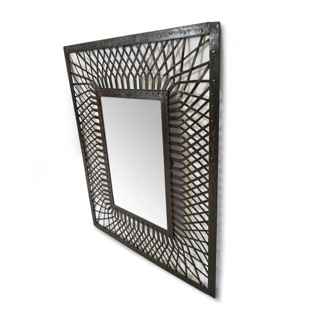 Vintage iron weave mirror featuring an intricately hand-forged lattice that radiates outward from a riveted inner frame....