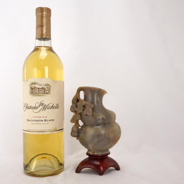 A hand carved pale gray soapstone in the shape of a double gourd vase with a sprig of fruit attached. The stone has...