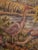 Hand-woven tapestry with a motif of wading birds with a plume in the view between flowers on a pond and a medieval village...