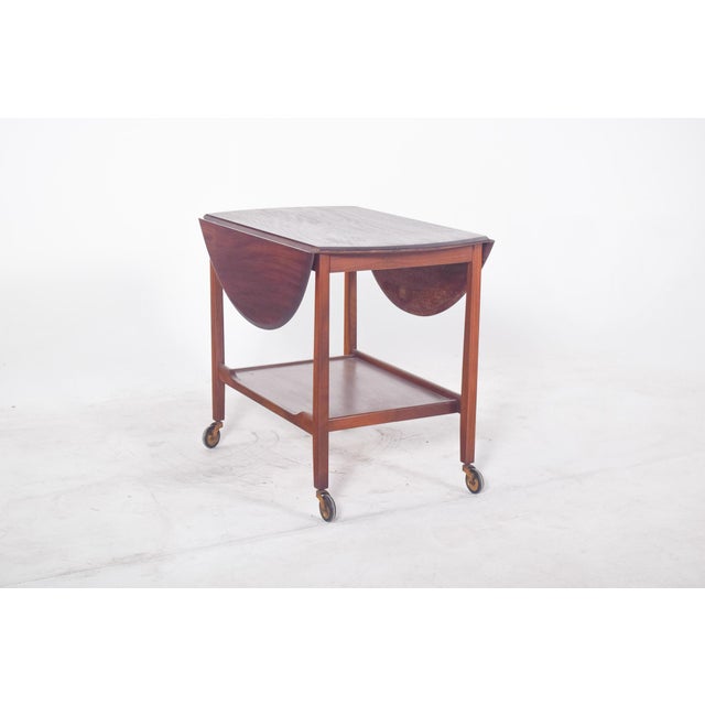 Tea trolley with flaps. Its slim, well-proportioned structure supports an oval top with hinged sides that can be raised to...