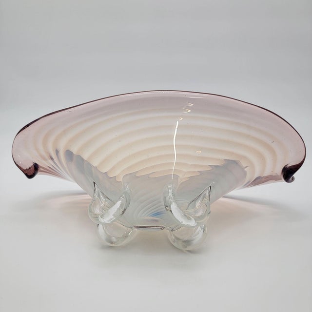 This exquisite hand-blown art glass bowl embodies elegance with its soft pink hues and rippled design. Elevated by sturdy...