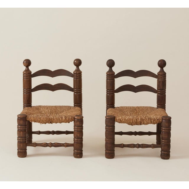 These elegant low fireside chairs by Charles Dudouyt have a woven rush seat with turned oak legs and ball structure on the...