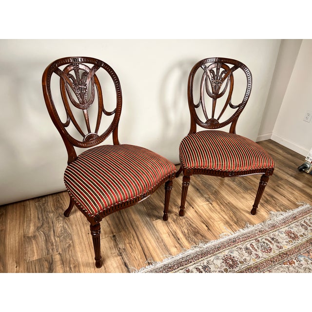 This handsome vintage pair of wheel back side chairs by Ardley Hall reflects the enduring appeal of classical English-...